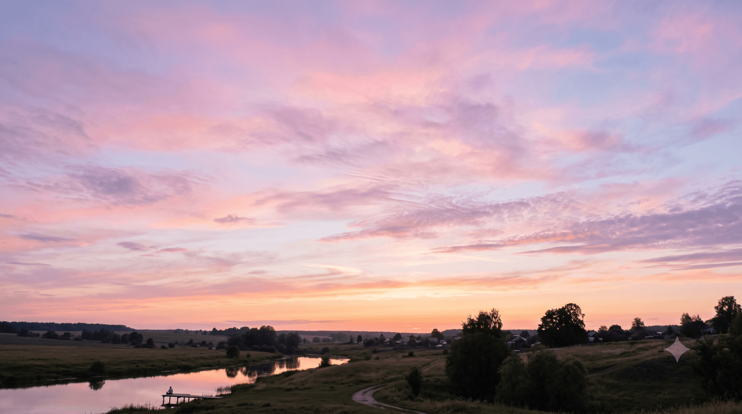 céu ao entardecer com nuvens em tons de rosa e lilás sobre paisagem tranquila
